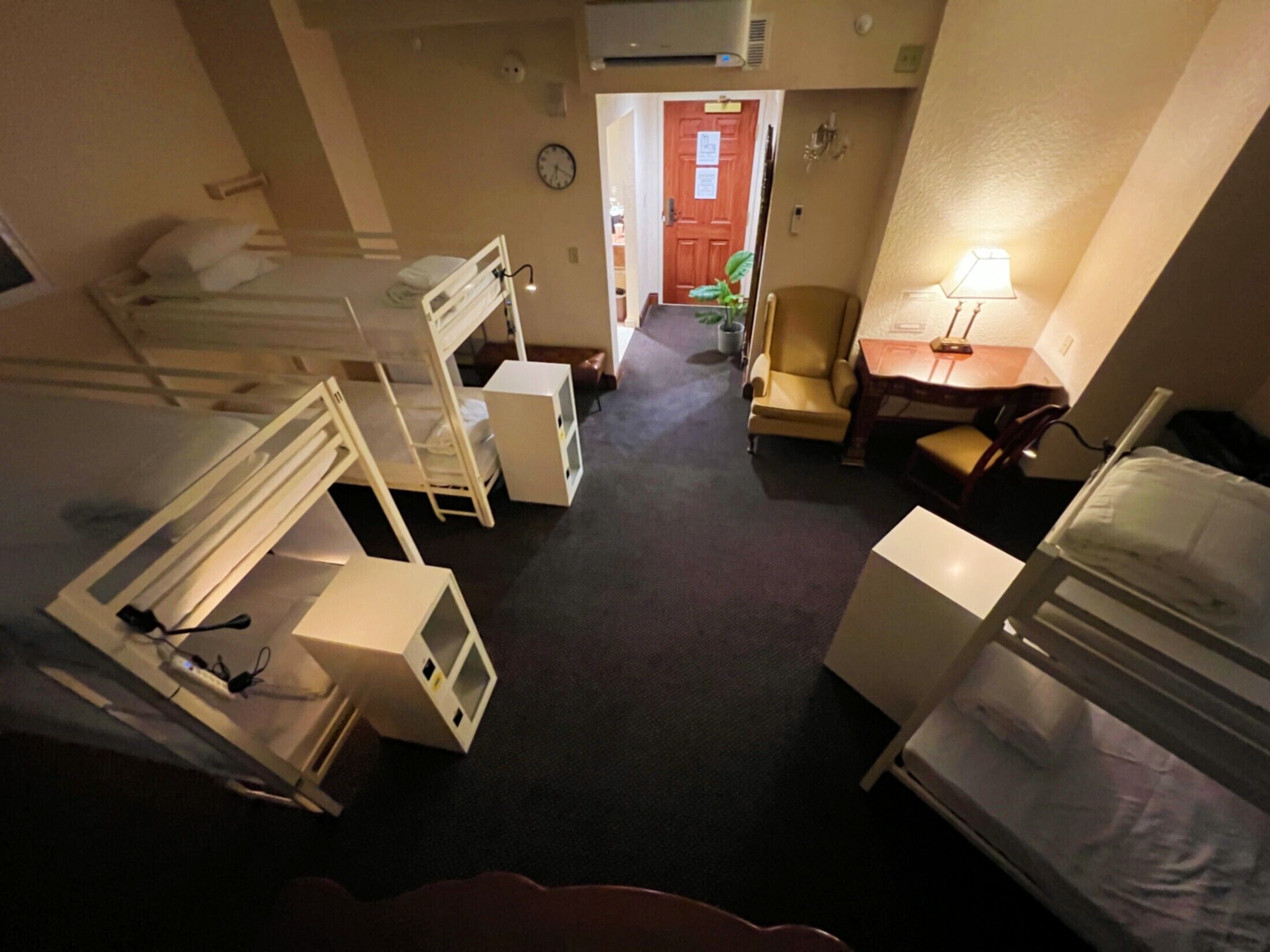 Habitació d'hotel compacta amb lliteres, escriptori, cadira i taula petita.