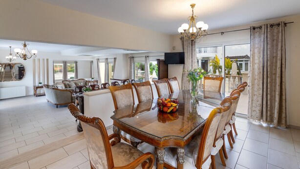 A spacious dining area with a glass-top table, surrounded by wooden chairs with cushioned seats.