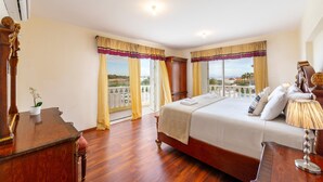 A hotel room with a large bed, wooden furniture, and a view of the landscape through the windows.
