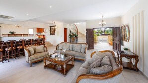 A spacious living area with a sofa set, wooden coffee table, and a dining area with chairs and a table.