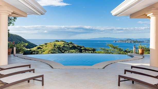 Une piscine avec vue sur la mer et les collines.
