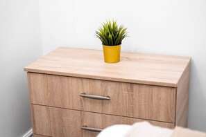 Una mesita de noche de madera con un cajón y una pequeña planta en maceta.