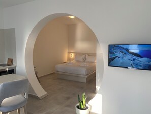 Ein modernes Hotelzimmer mit einem Bett, einem Fernseher, einem Schreibtisch und einer Zimmerpflanze.