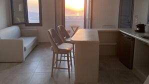Una cocina moderna con comedor, sofá y vistas al atardecer.