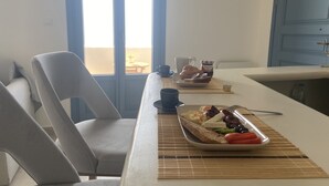 Un comedor con una mesa dispuesta para el desayuno, que incluye pan, queso y verduras.