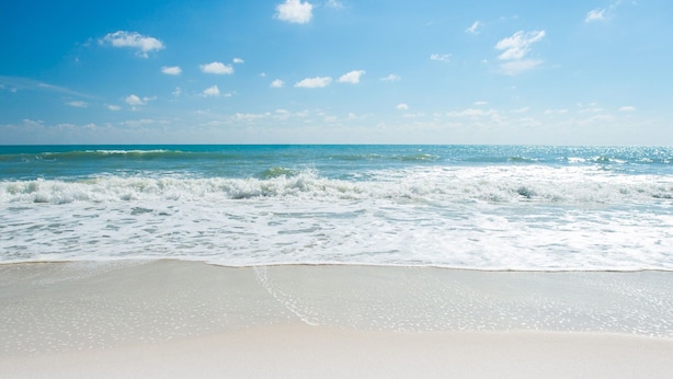 Una playa con olas y cielo despejado.