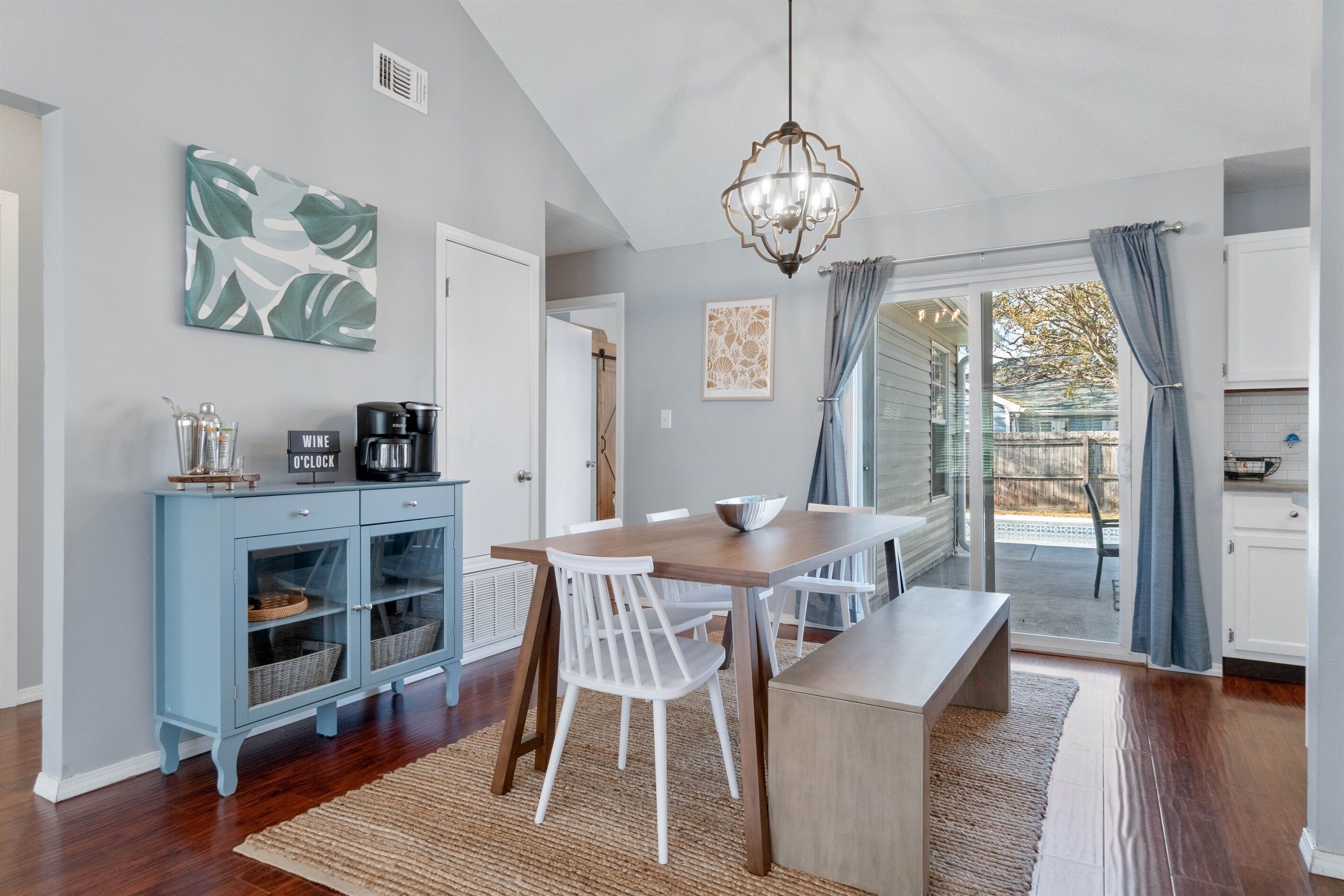 A dining area with a wooden table, white chairs, and a blue cabinet with glass doors.