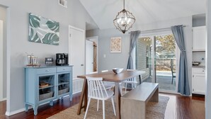 Un comedor con una mesa de madera, sillas blancas y un mueble azul con puertas de vidrio.
