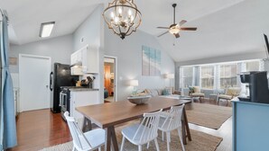 Una cocina amplia con comedor, muebles de cocina blancos, una araña y un ventilador de techo.