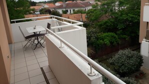 Ein Balkon mit wei ßer Reling, einem Tisch und Stühlen.