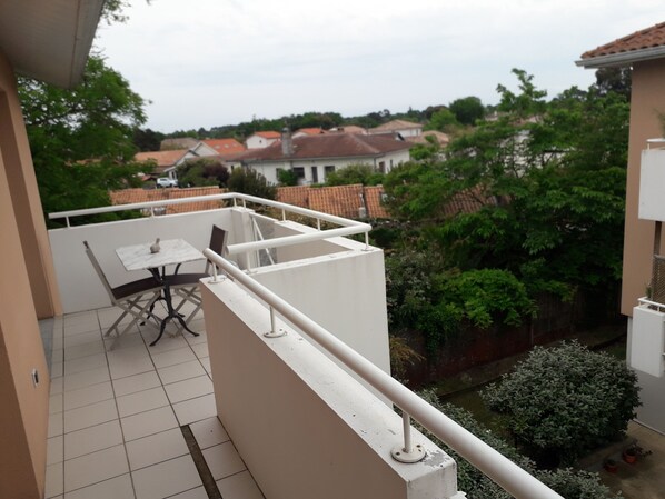 A balcony with a white railing, a table, and chairs.