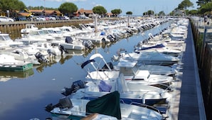 Ein Yachthafen mit zahlreichen Booten, die in Reih und Glied vor Anker liegen, ein Holzsteg daneben und ein klarer Himmel.