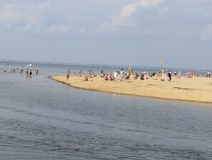 A beach with people sunbathing and swimming. - 2-bedroom apartment close to port, beach, stores, train station  (Gujan-Mestras)
