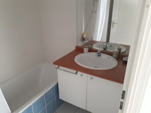 A bathroom with a bathtub, a sink, and a mirror.