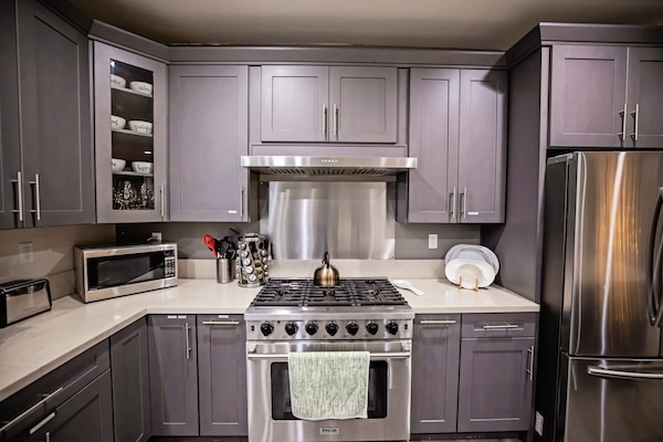 Een koelkast, een magnetron, keukenrol, eettafels