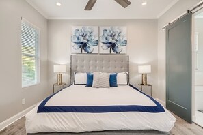 Quarto com uma cama grande, duas luminárias fixadas na parede e duas pinturas florais sobre a cama.