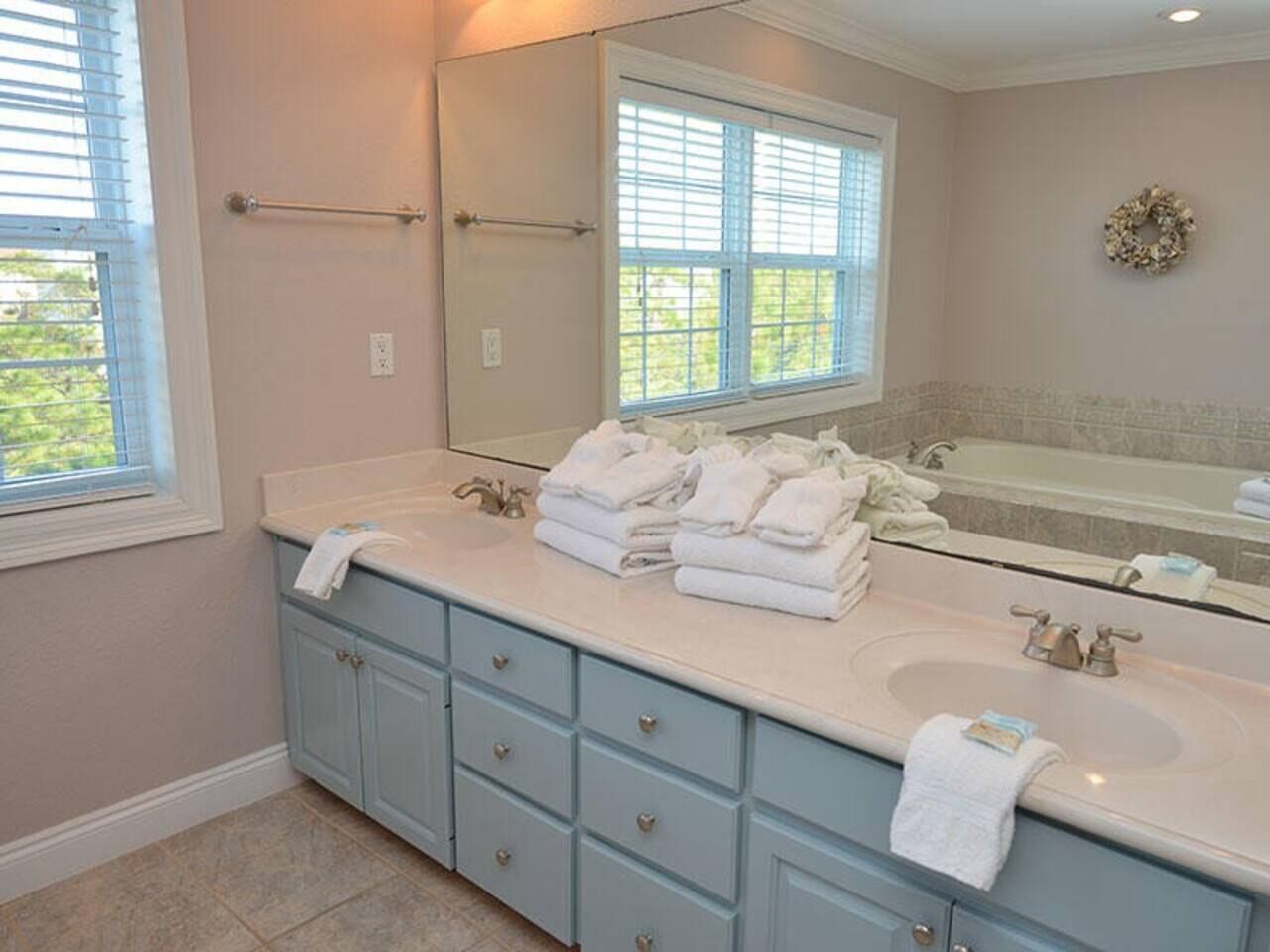 A bathroom with two sinks, a large mirror, and a window with blinds.
