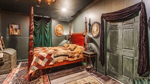 A room with a four-poster bed, a green curtain, a vintage lamp, and a wooden chest. - The Burrow (Chickamauga)