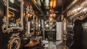 A luxurious bathroom with ornate mirrors, a vanity, and a chandelier. - The Burrow (Chickamauga)