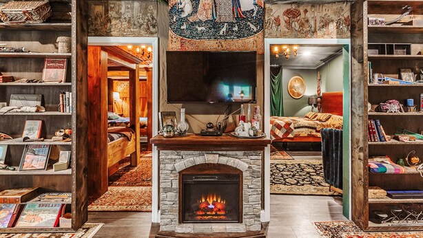 A cozy room with a fireplace, a television, and a bookshelf filled with books. - The Burrow (Chickamauga)