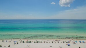 A beach with clear turquoise water, white sand, and umbrellas.