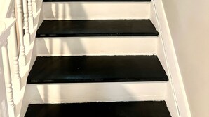 Eine Treppe mit weißen Balustraden und schwarzen Stufen, die zu einer Empore mit einem Fenster führt.