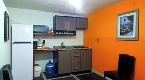 Compact kitchen with a refrigerator, microwave, gas stove, sink, and cabinets.