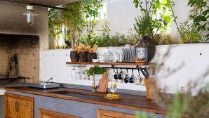 A kitchen with wooden cabinets, a countertop, hanging utensils, and shelves with kitchenware. - Villa Kucha 26b with Pool & Seaview (Vrbnik (Krk))