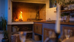 A cozy kitchen with a fireplace, wooden cabinets, and a shelf with kitchenware. - Villa Kucha 26b with Pool & Seaview (Vrbnik (Krk))