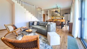 A modern living room with a sofa, coffee table, and a unique woven chair. A staircase leads to an upper level. - Villa Kucha 26b with Pool & Seaview (Vrbnik (Krk))