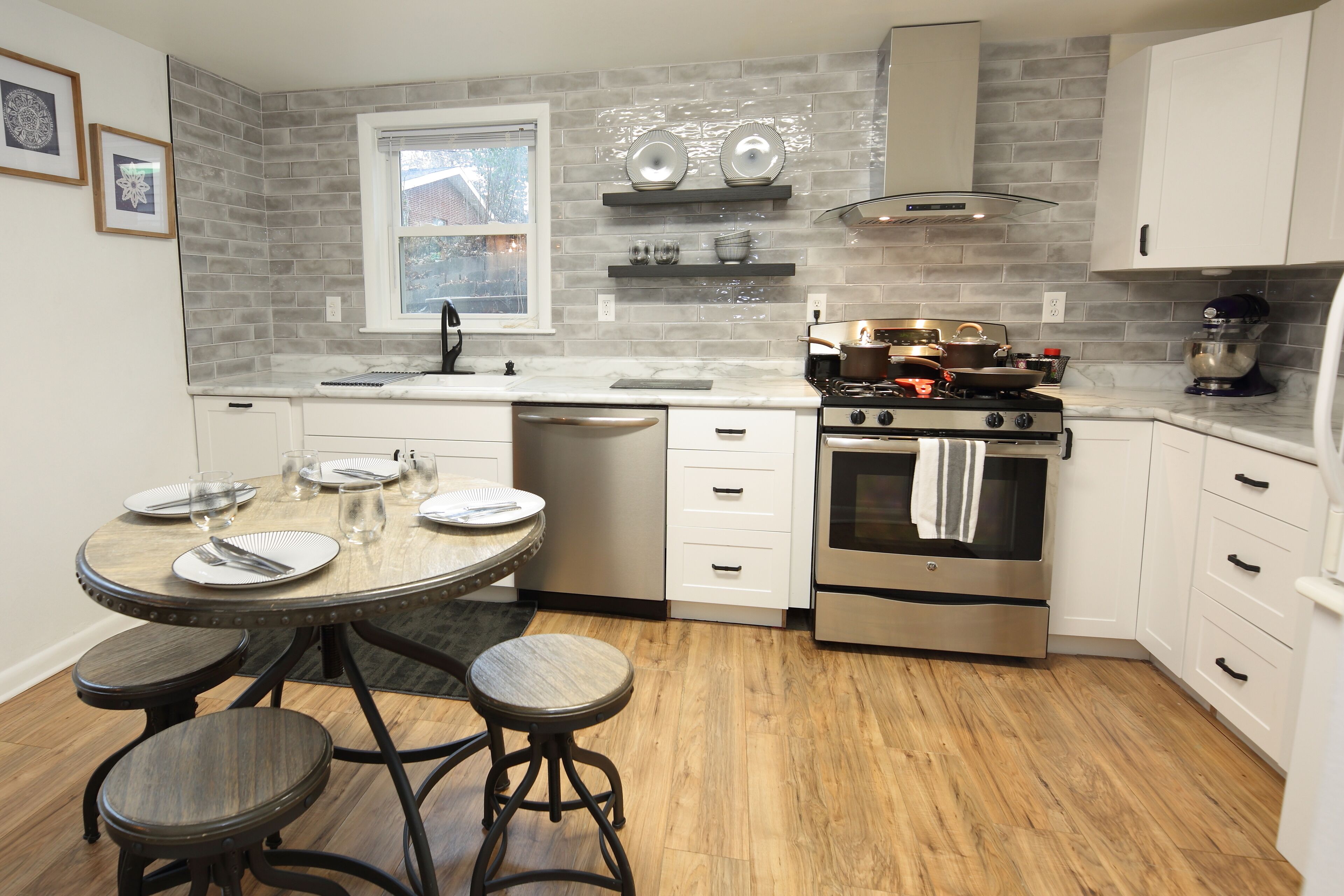 Una cocina moderna con una isla central, armarios blancos, una estufa de acero inoxidable y un ventanal con vistas.