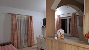 Ett hotellrum med ett skrivbord i trä, en stol, en säng med ett randigt överkast och en tv på väggen.
