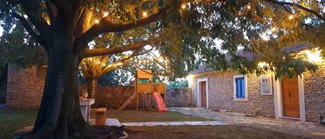 Un edificio de piedra con puerta de madera, pared de ladrillo y un árbol en primer plano.