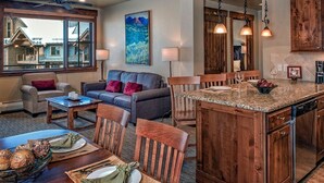Un vaste espace de vie doté d’une grande fenêtre, d’une cheminée et d’un coin repas avec une table et des chaises en bois.