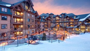 Un chalet à étages doté d’une cour enneigée et d’un éclairage chaleureux.