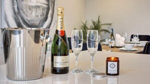 Ein Tisch mit einer Champagnerflasche, Gläsern, einer Kerze und einem Metallbehälter.