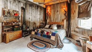 Una camera da letto rustica con un letto di legno, un vecchio stufa e un'atmosfera accogliente.