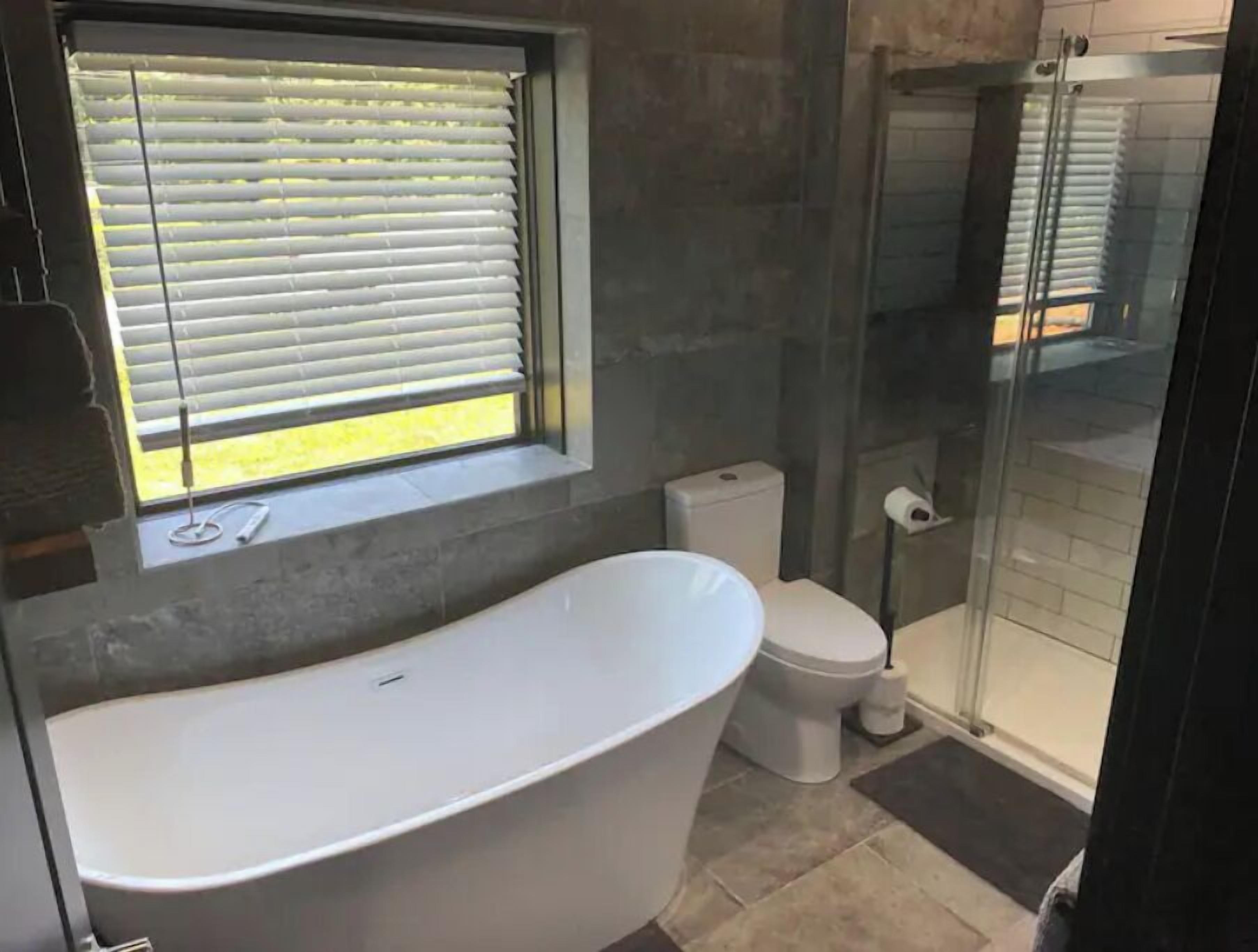 A modern bathroom with a freestanding bathtub, a toilet, and a glass shower enclosure.