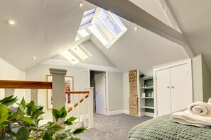 Cozy retreat with a sloped ceiling, skylights, and a comfortable bed.