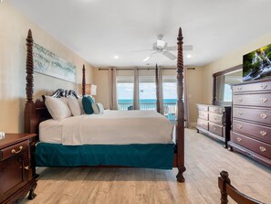 A four-poster bed with a balcony view, a dresser, and a ceiling fan.