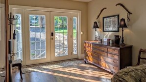 A room with a large sliding glass door leading to a patio, a wooden dresser with drawers, two wall-mounted lamps, and a framed map on the wall. - Private Historic House, in Downtown Bristol Virginia! (Bristol)