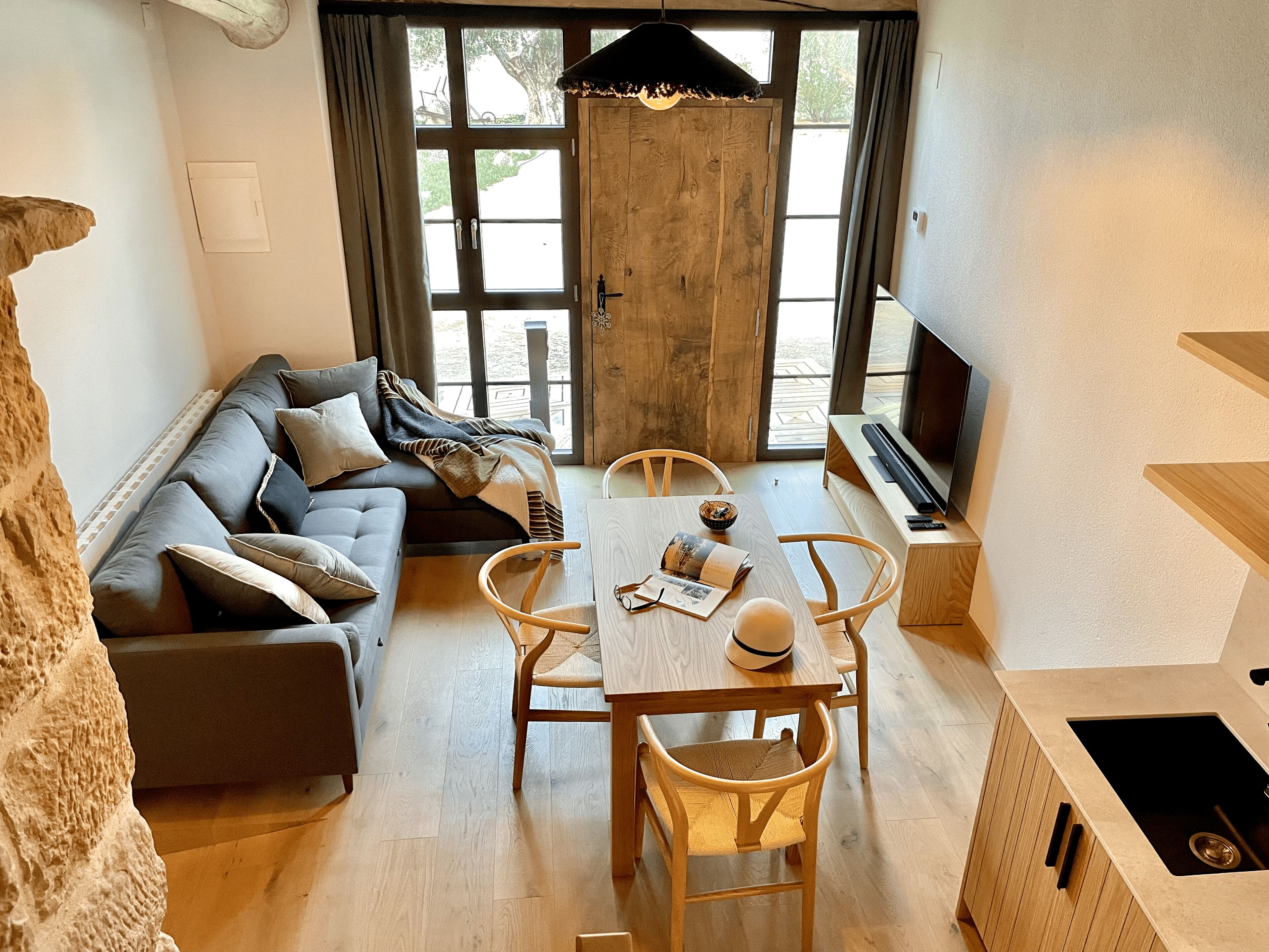 Una sala moderna con sofá, mesa de comedor, sillas y televisor.