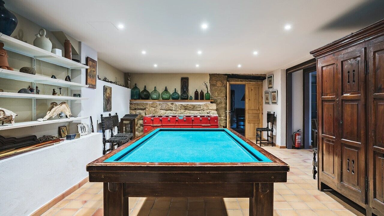 Una mesa de billar en una habitación con estanterías a la izquierda y un mueble de madera a la derecha.