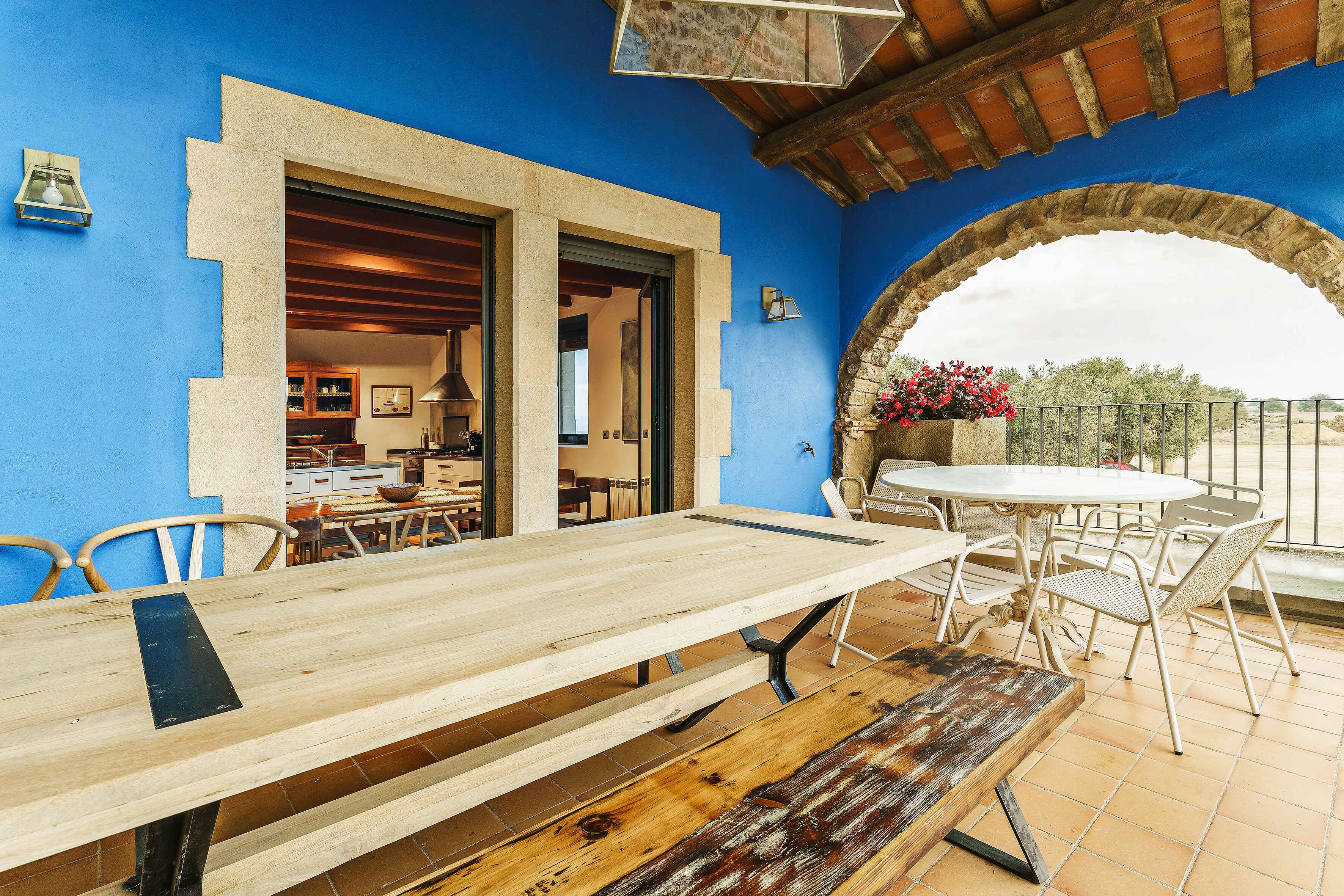 Un comedor con mesa y sillas de madera, un arco y vistas al exterior.