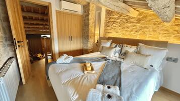 A bedroom with a large bed, wooden wardrobe, and a stone wall.