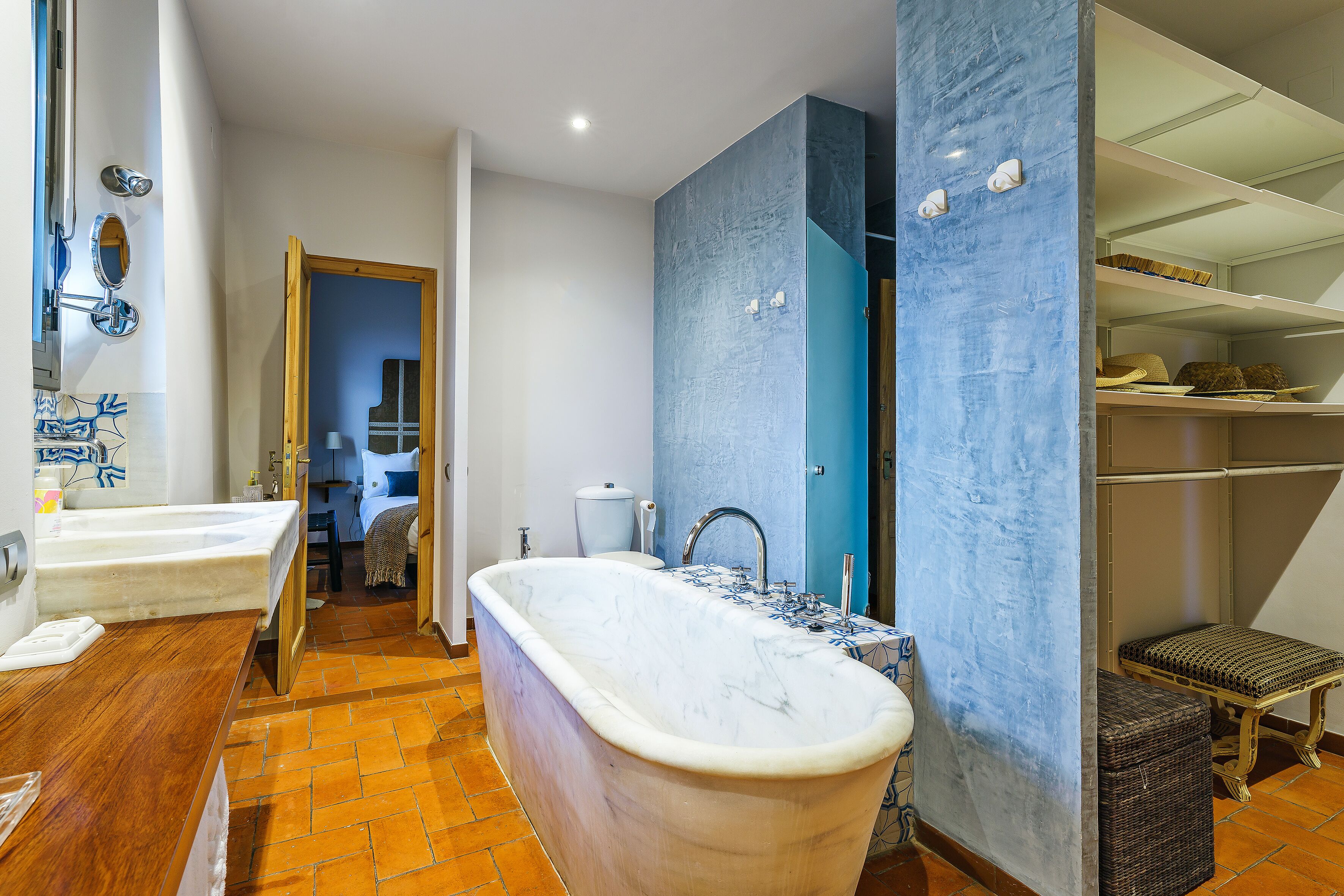 Un baño con una bañera independiente, un tocador de madera y suelo de baldosas.