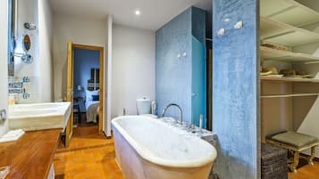 Un baño con una bañera independiente, un tocador de madera y suelo de baldosas.