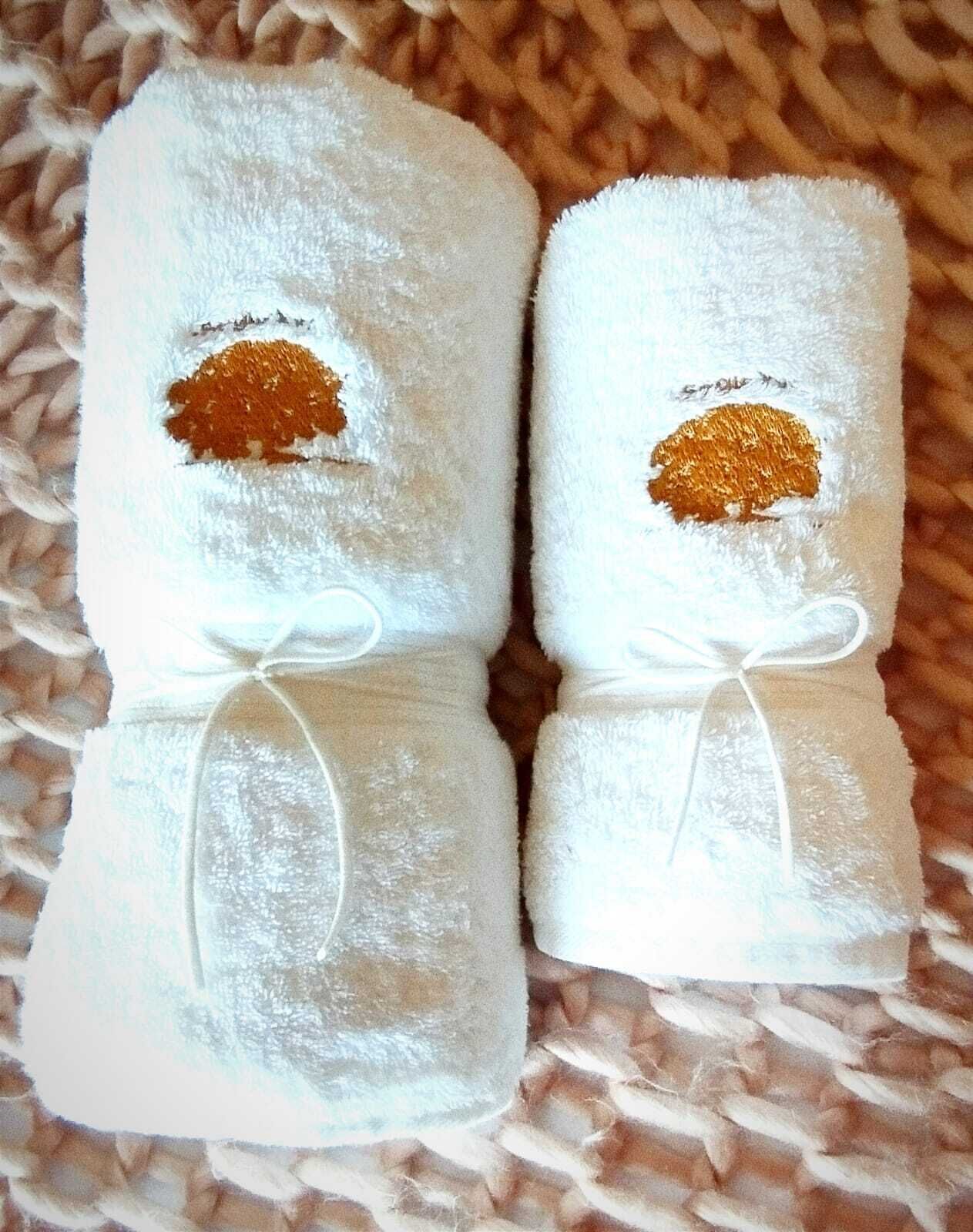 Dues tovelles blanques amb brodat daurat i una cinta blanca lligada al voltant.