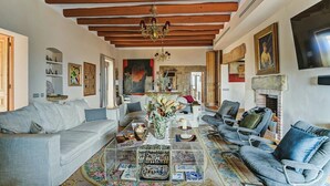 A spacious living room with a sofa, armchairs, a coffee table with decorative items, and a fireplace. - Masia de Queralt (Els Plans de Sio)