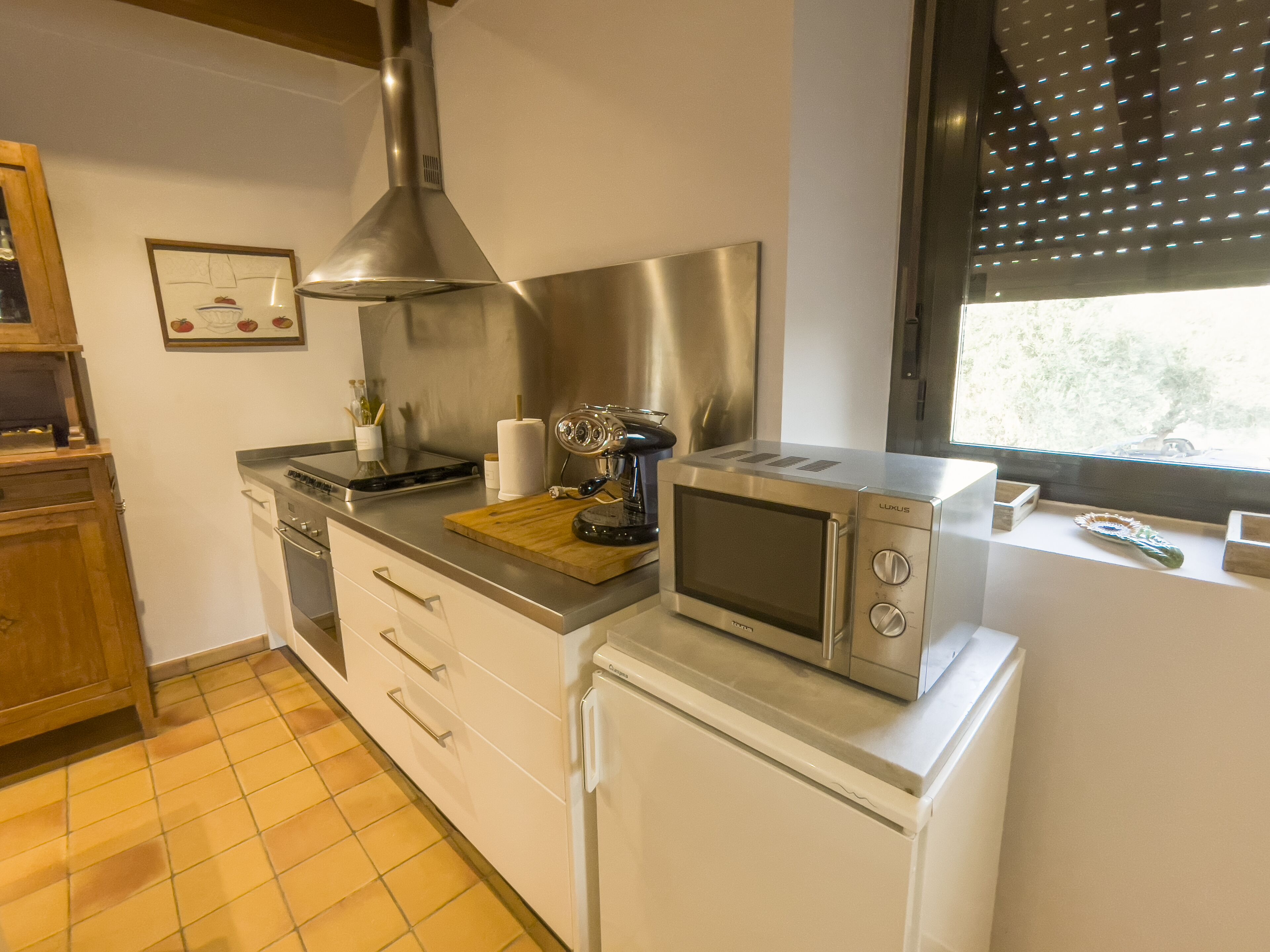 A compact kitchen with a microwave, toaster, and a wooden cutting board.